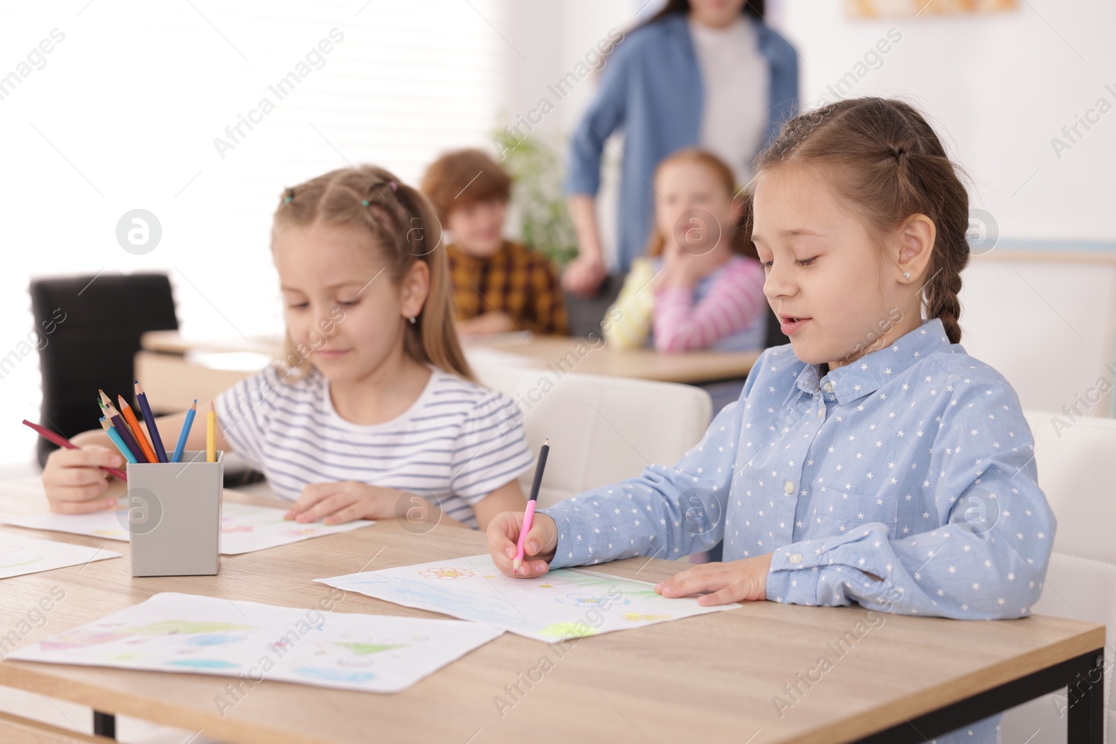 Kids with teacher at painting lesson indoors, selective focus. Learning to draw Photo of Kids with teacher at painting lesson indoors, selective focus. Learning to draw