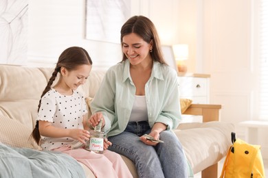 Photo of Mother giving pocket money to her daughter on sofa at home