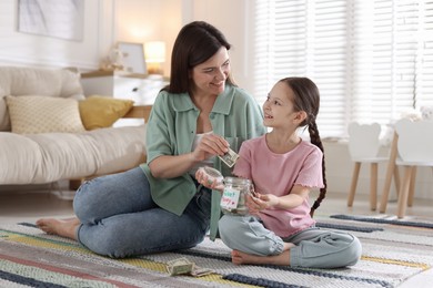 Photo of Mother giving pocket money to her daughter at home