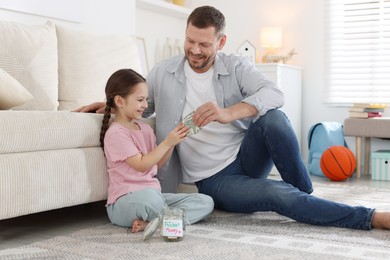 Photo of Father giving his daughter pocket money at home