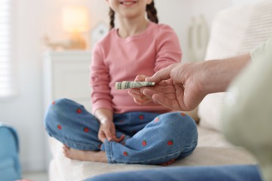 Photo of Father giving his daughter pocket money on sofa at home, closeup