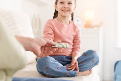 Photo of Father giving his daughter pocket money on sofa at home, closeup