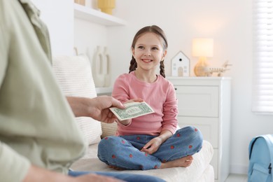 Photo of Father giving his daughter pocket money on sofa at home, closeup