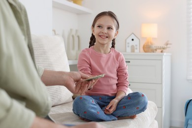 Photo of Father giving his daughter pocket money on sofa at home, closeup