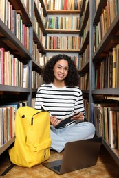 Photo of Woman with book studying near shelves in public library