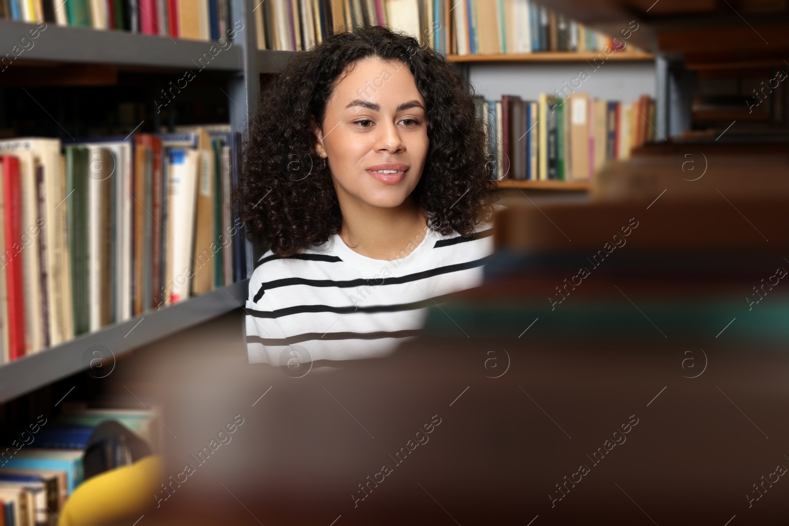 Woman choosing book from shelf in public library Photo of Woman choosing book from shelf in public library