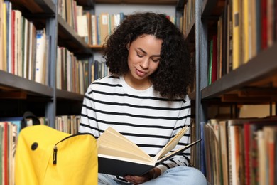 Photo of Woman reading book near shelves in public library