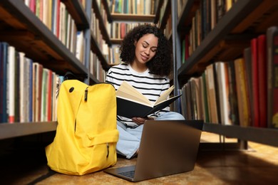 Photo of Woman with book studying near shelves in public library