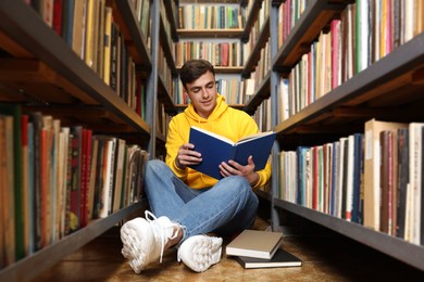 Photo of Man reading book near shelves in public library
