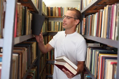 Photo of Man choosing book from shelf in public library