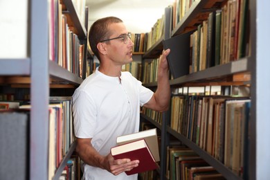 Photo of Man choosing book from shelf in public library