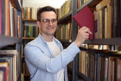 Photo of Man taking book from shelf in public library