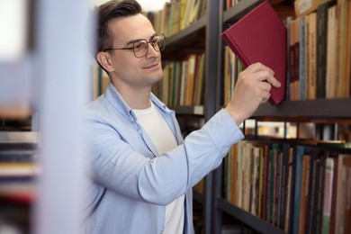Photo of Man taking book from shelf in public library