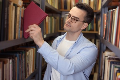 Photo of Man taking book from shelf in public library