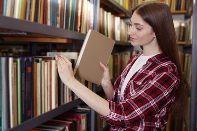 Photo of Woman taking book from shelf in public library