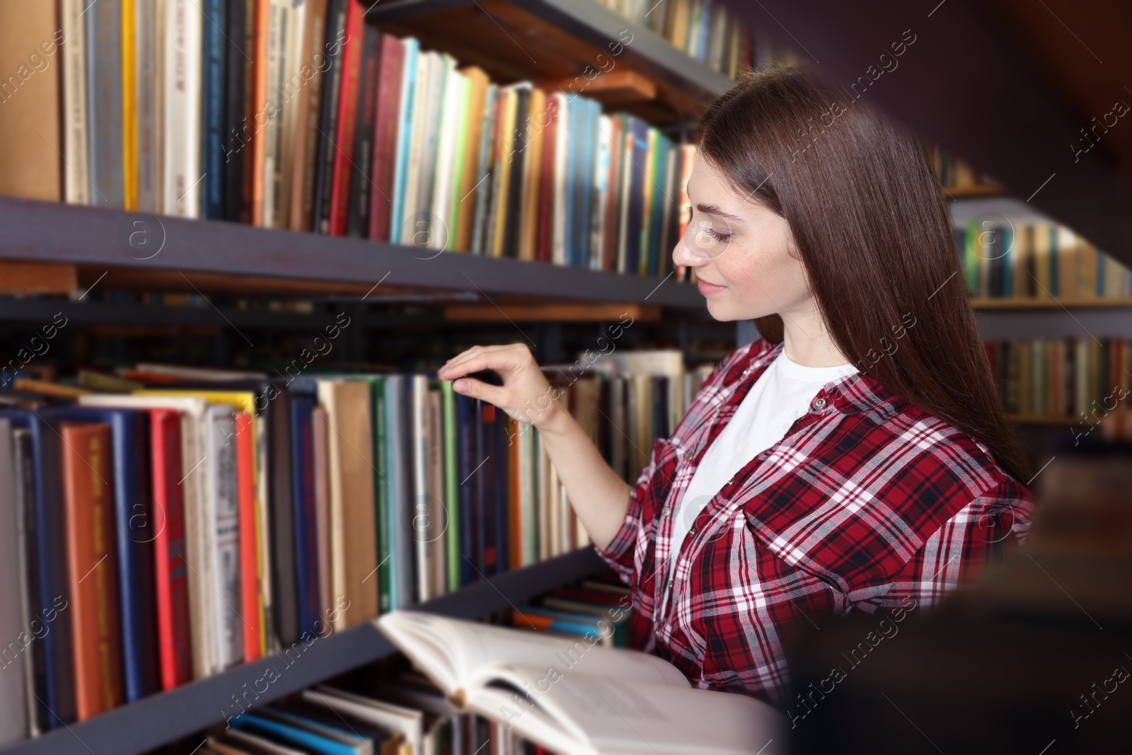 Woman with book near shelves in public library Photo of Woman with book near shelves in public library