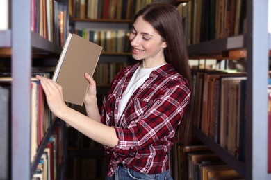 Photo of Woman taking book from shelf in public library