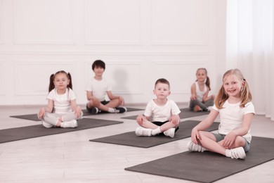 Photo of Group of children sitting on yoga mats in class