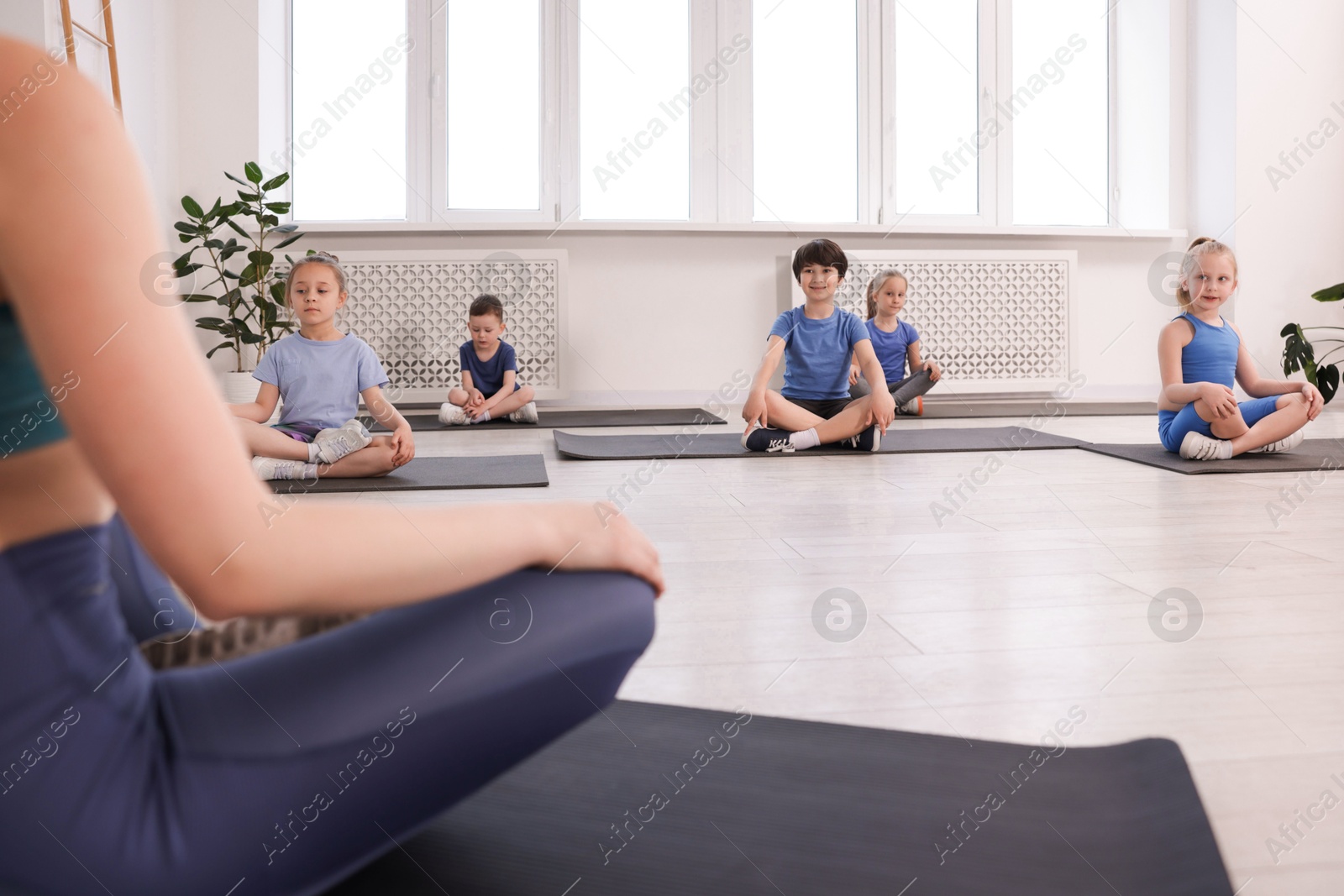 Group of children practicing yoga with coach on mats in class, selective focus Photo of Group of children practicing yoga with coach on mats in class, selective focus