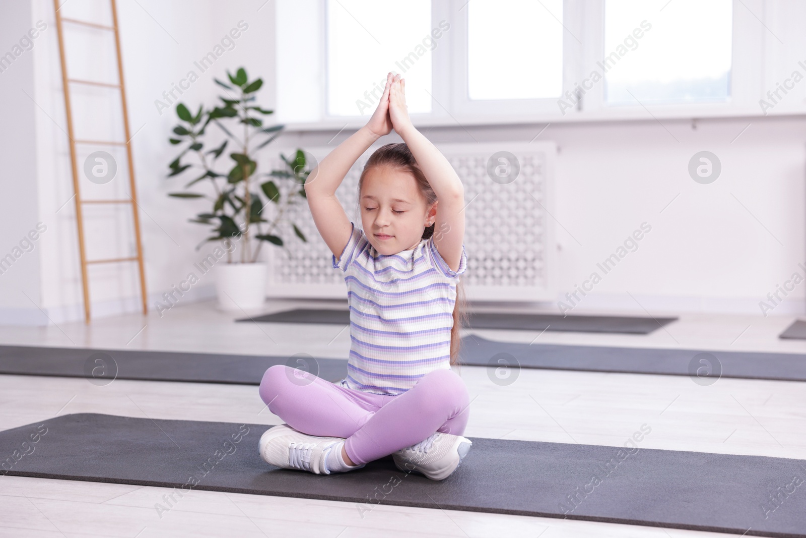Cute girl meditating on yoga mat indoors Photo of Cute girl meditating on yoga mat indoors