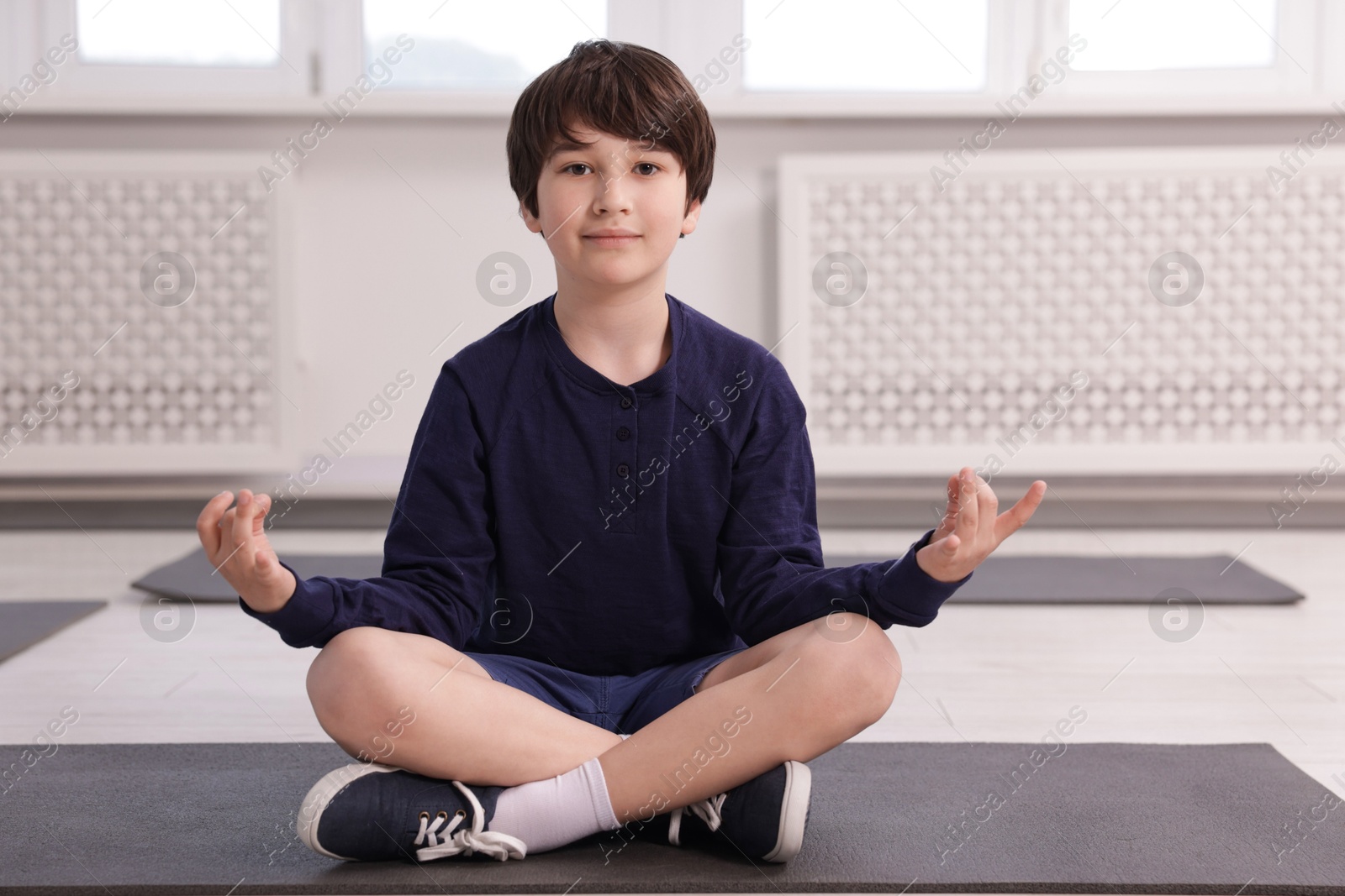 Cute boy practicing yoga on mat indoors Photo of Cute boy practicing yoga on mat indoors