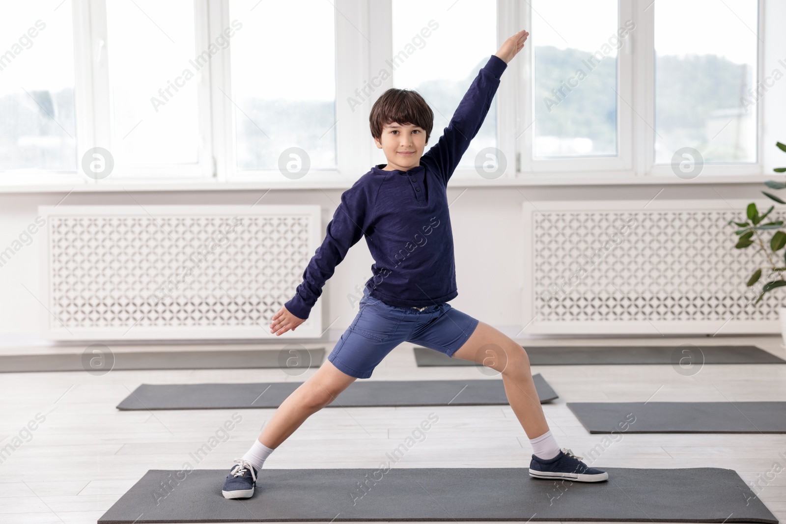 Cute boy practicing yoga on mat indoors Photo of Cute boy practicing yoga on mat indoors