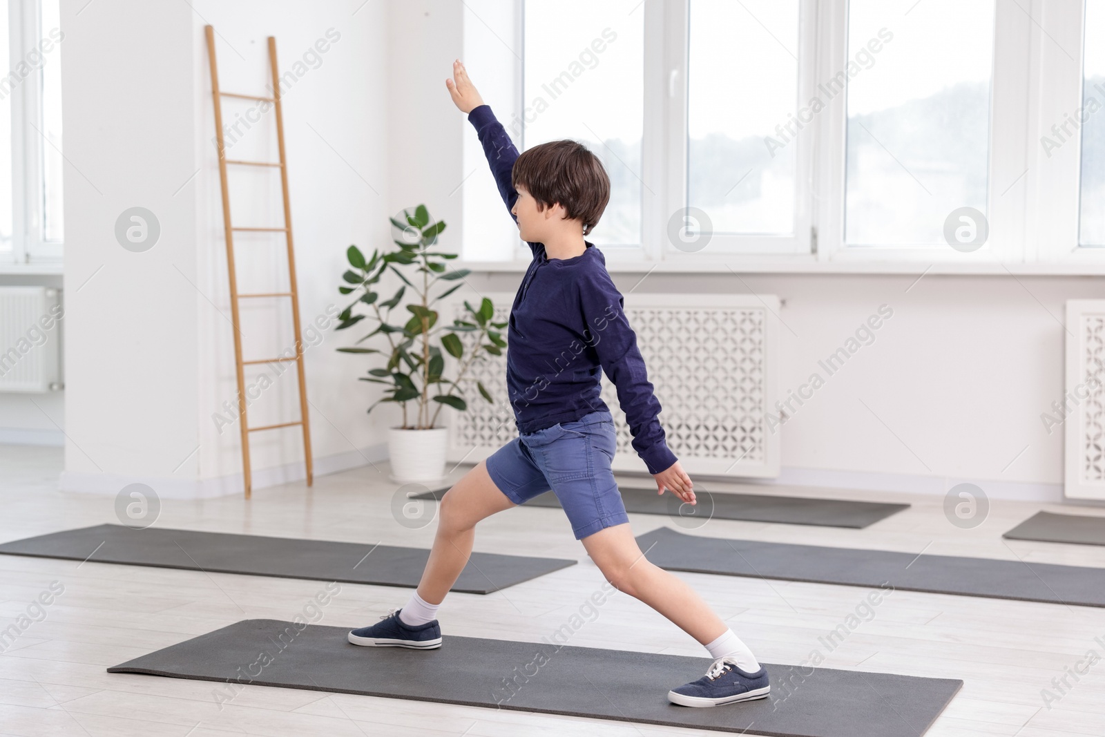 Cute boy practicing yoga on mat indoors Photo of Cute boy practicing yoga on mat indoors