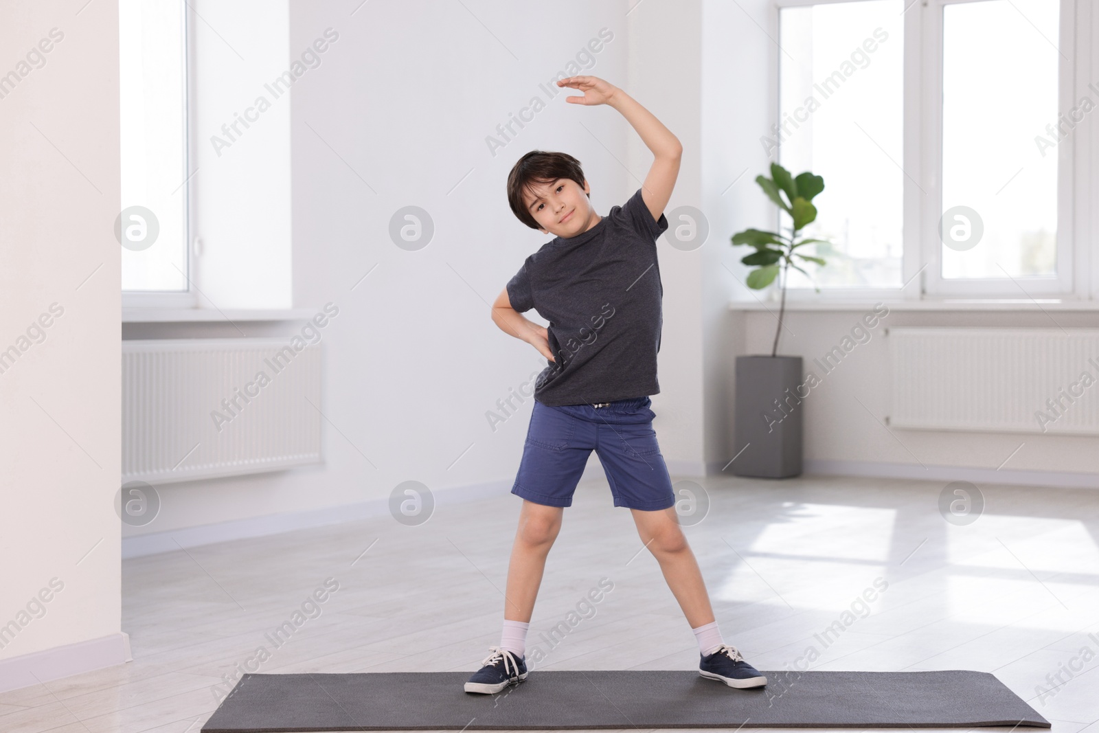 Cute boy exercising on yoga mat indoors Photo of Cute boy exercising on yoga mat indoors