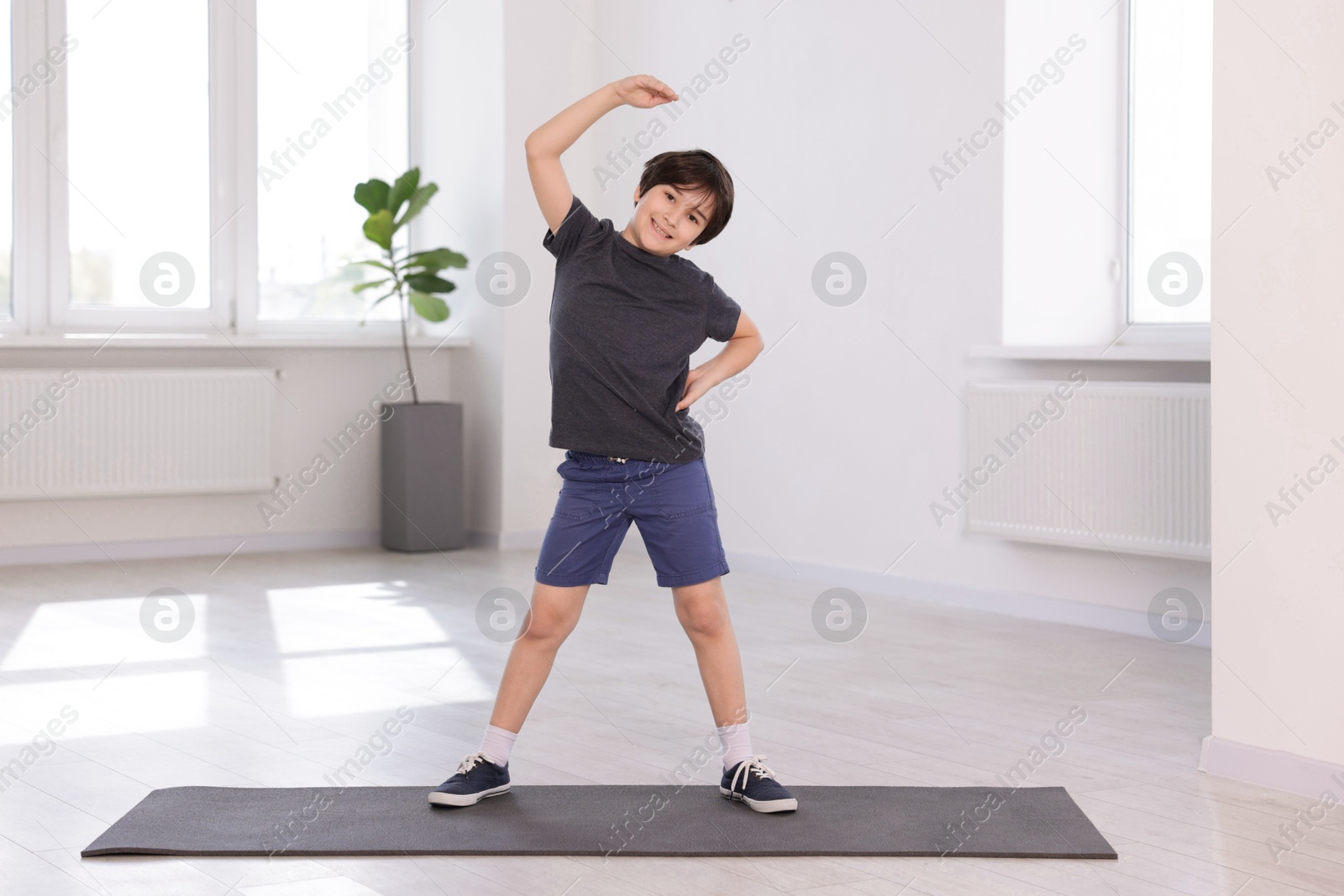 Cute boy exercising on yoga mat indoors Photo of Cute boy exercising on yoga mat indoors