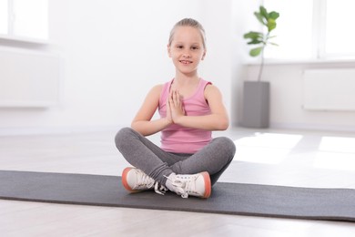 Photo of Happy girl practicing yoga on mat indoors
