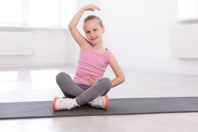 Photo of Happy girl practicing yoga on mat indoors