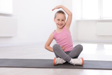 Photo of Happy girl practicing yoga on mat indoors