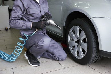 Photo of Mechanic changing tire at car service, closeup