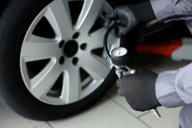 Photo of Mechanic inflating new tire at car service, closeup