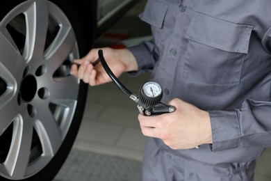 Photo of Mechanic inflating new tire at car service, closeup