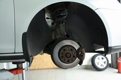 Photo of Lifted automobile during tire change at car service, closeup