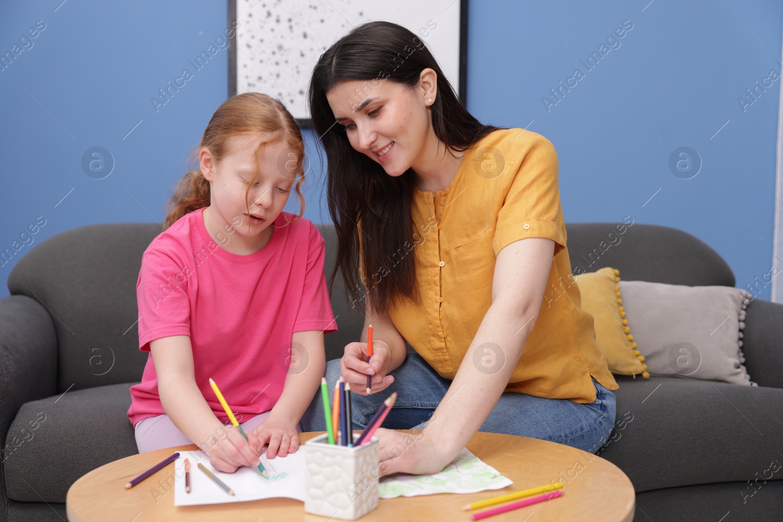 Mother teaching her daughter to draw at table indoors Photo of Mother teaching her daughter to draw at table indoors