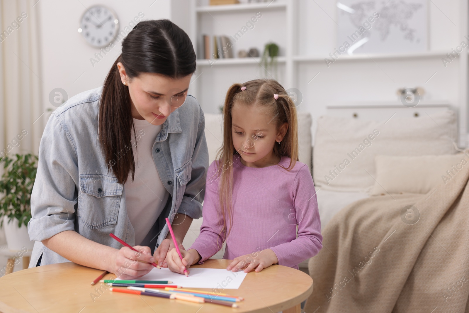 Mother teaching her daughter to draw at table indoors, space for text Photo of Mother teaching her daughter to draw at table indoors, space for text