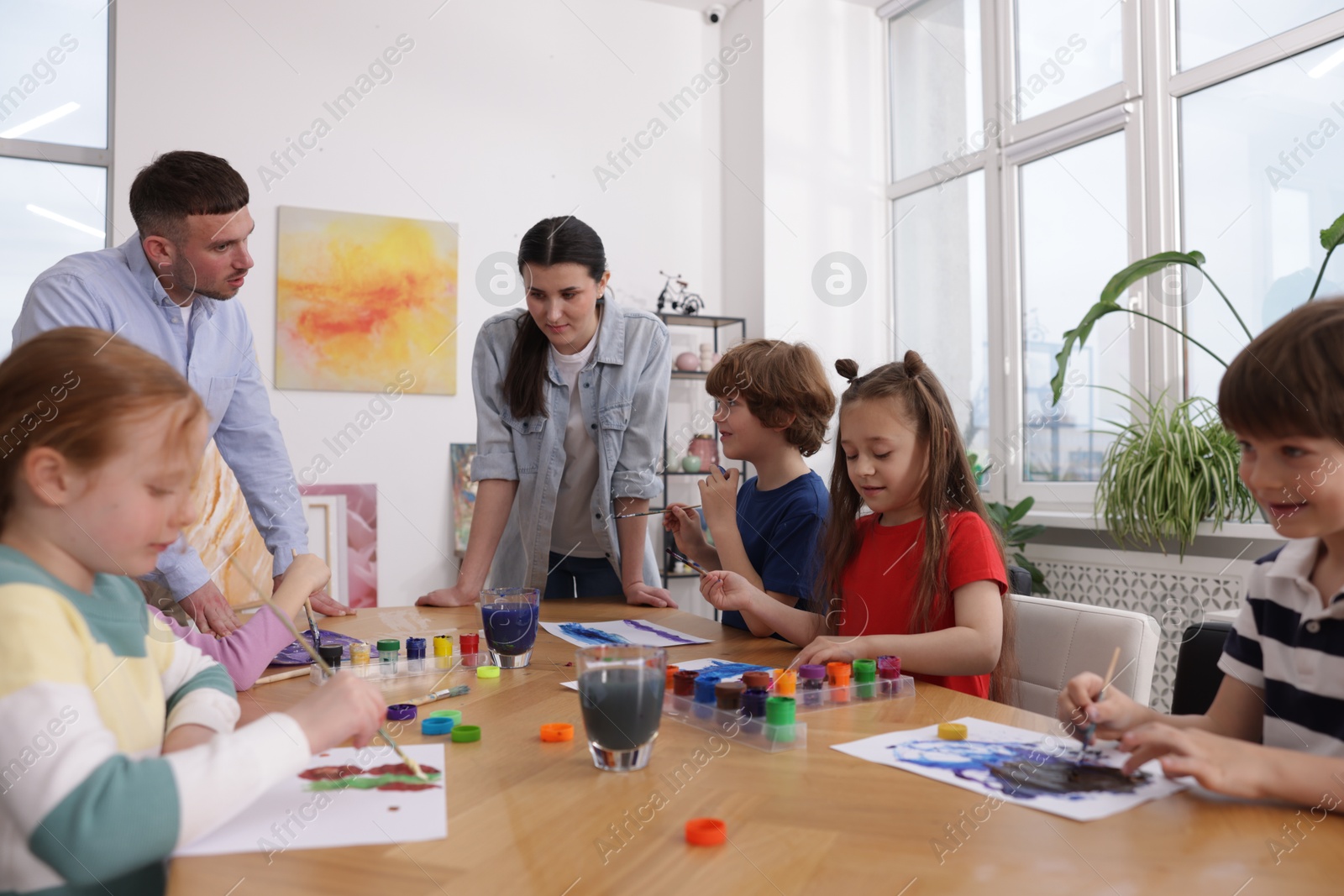 Kids with teachers at painting lesson indoors. Learning to draw Photo of Kids with teachers at painting lesson indoors. Learning to draw
