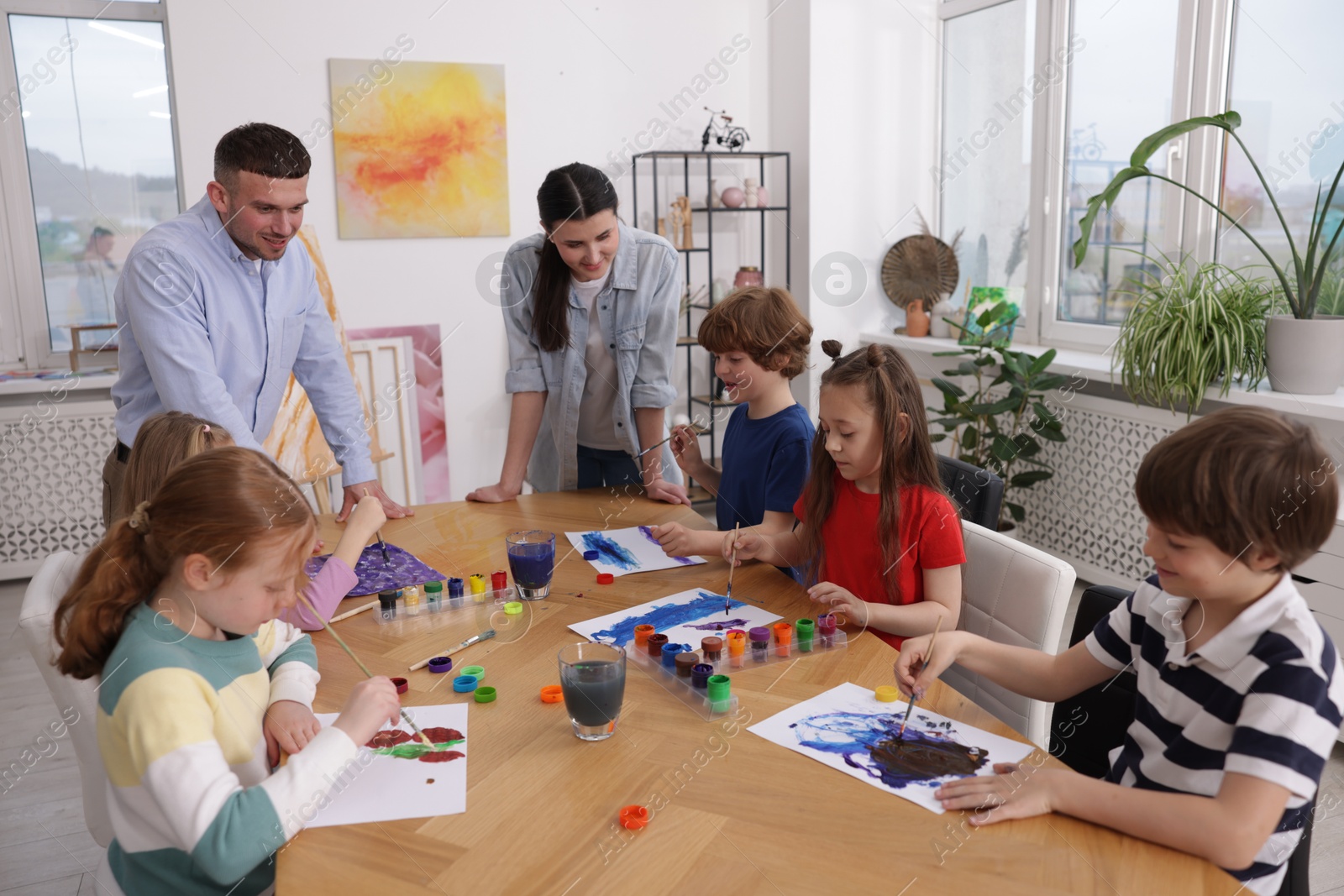 Kids with teachers at painting lesson indoors. Learning to draw Photo of Kids with teachers at painting lesson indoors. Learning to draw