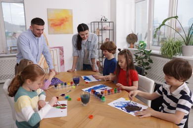 Photo of Kids with teachers at painting lesson indoors. Learning to draw