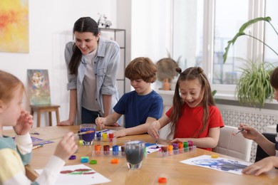 Photo of Woman teaching kids to draw at painting lesson indoors