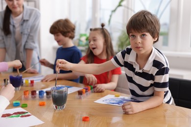Photo of Woman teaching kids to draw at painting lesson indoors, selective focus