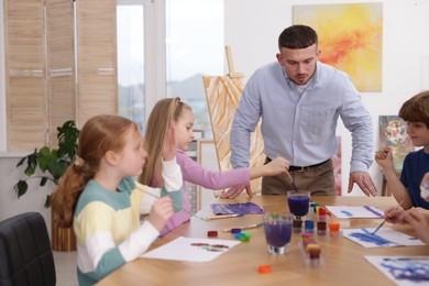 Photo of Kids with teacher at painting lesson. Learning to draw
