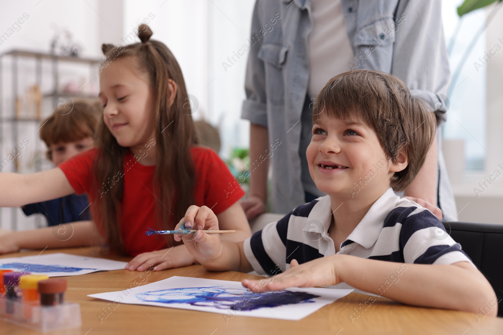 Kids with teacher at painting lesson. Learning to draw Photo of Kids with teacher at painting lesson. Learning to draw