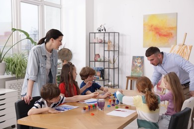 Photo of Kids with teachers at painting lesson indoors. Learning to draw