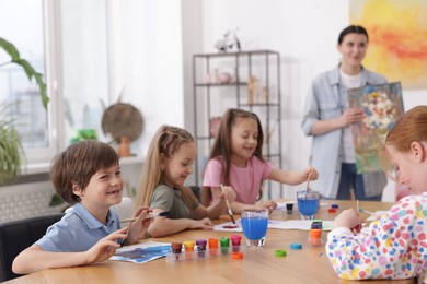 Photo of Kids with teacher at painting lesson indoors, selective focus. Learning to draw
