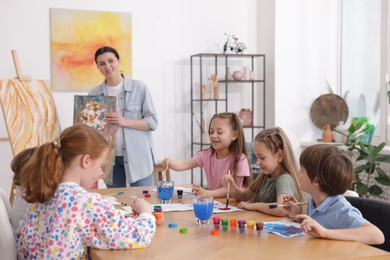 Photo of Kids with teacher at painting lesson indoors, selective focus. Learning to draw