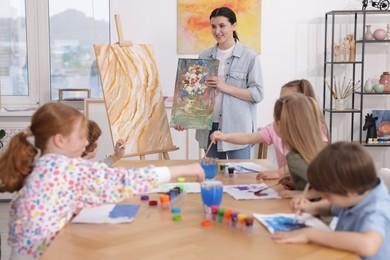 Photo of Kids with teacher at painting lesson indoors. Learning to draw