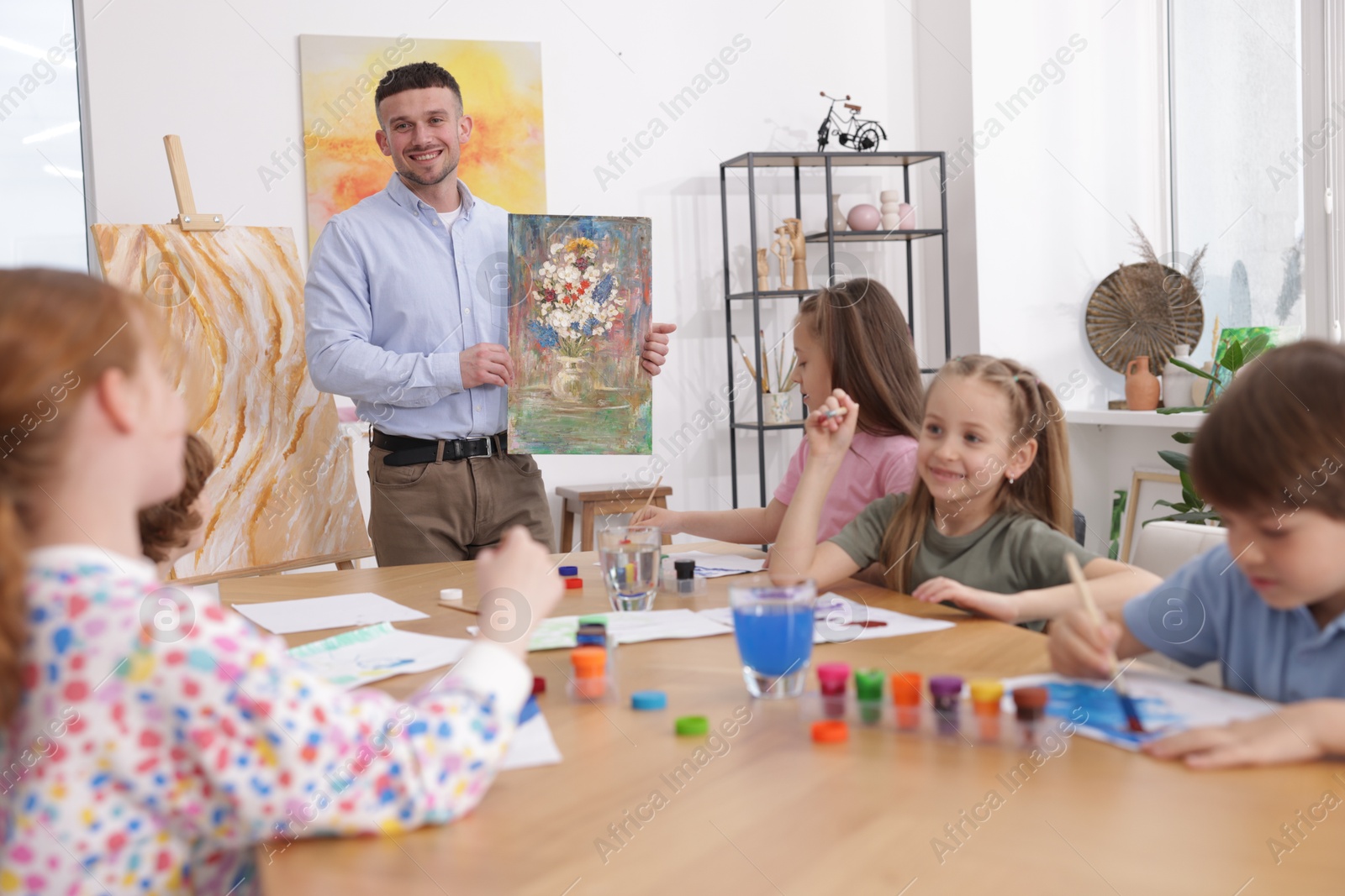 Kids with teacher at painting lesson indoors. Learning to draw Photo of Kids with teacher at painting lesson indoors. Learning to draw